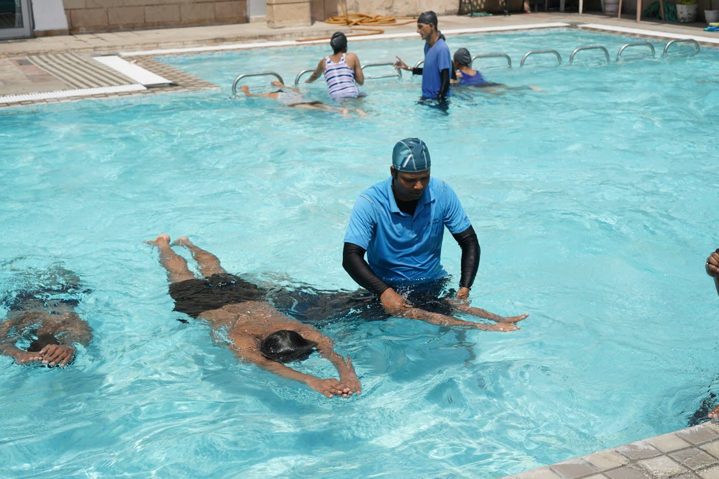 A swimming instructor in the pool supporting a swimmer